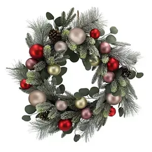 A decorative wreath featuring frosted greenery, red, gold, and pink ornaments, pine cones, and eucalyptus leaves.