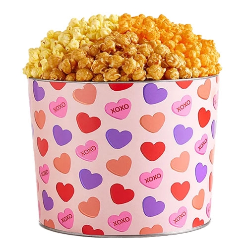 Large tin featuring a Valentine's Day theme with hearts and \“XOXO\“ text, filled with three types of popcorn: butter, caramel, and cheese.