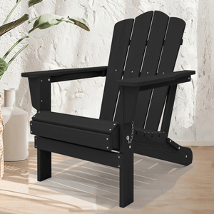 A black Adirondack chair with a slatted backrest and wide armrests, set on a light wooden floor with decorative plants nearby.