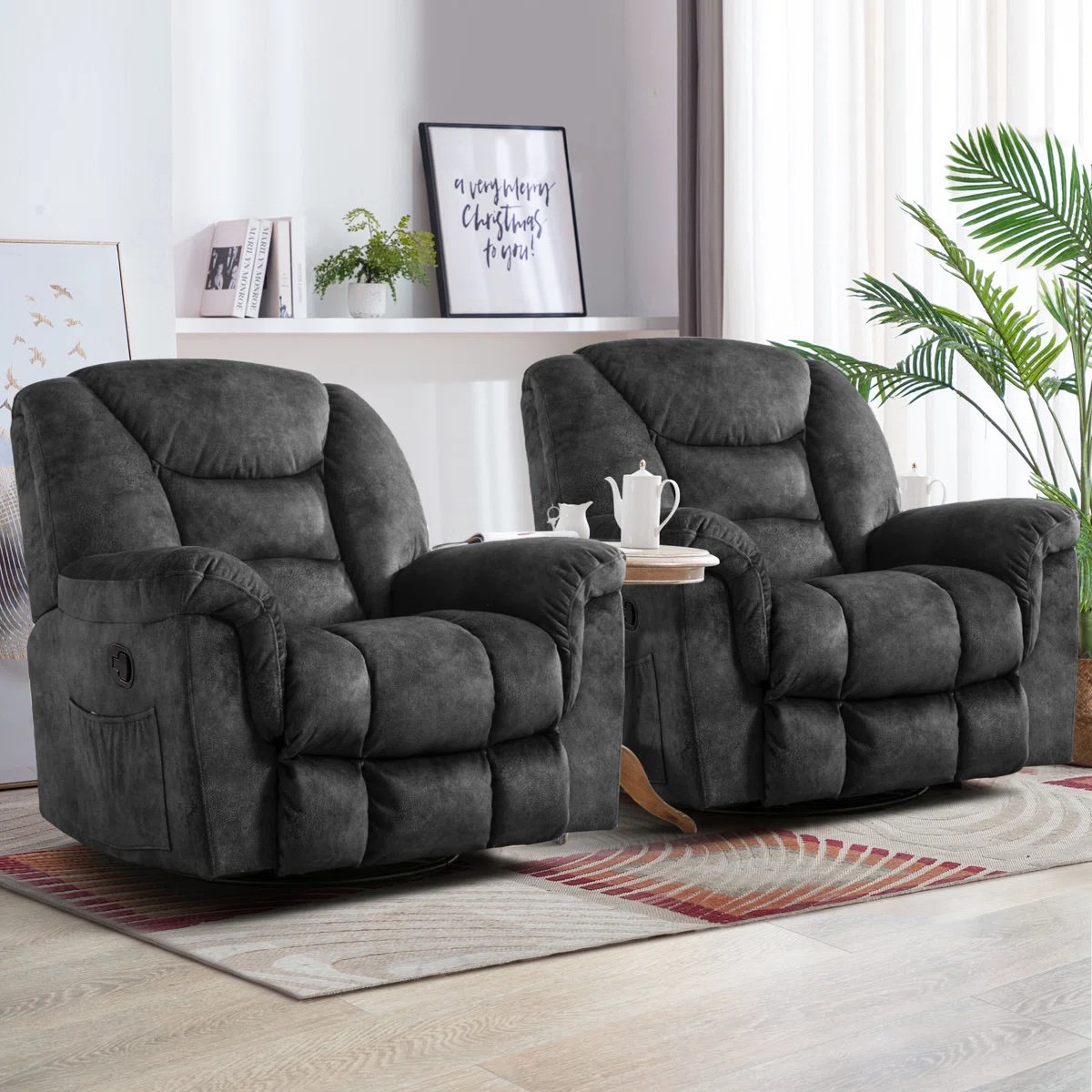 Two plush, dark gray recliners are positioned on a geometric-patterned rug in a well-lit room, complemented by a small round side table holding a tea set.
