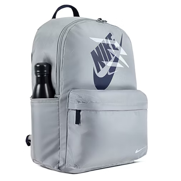 A gray Nike backpack featuring the Nike logo, with a front zippered pocket and a side pocket holding a black water bottle.