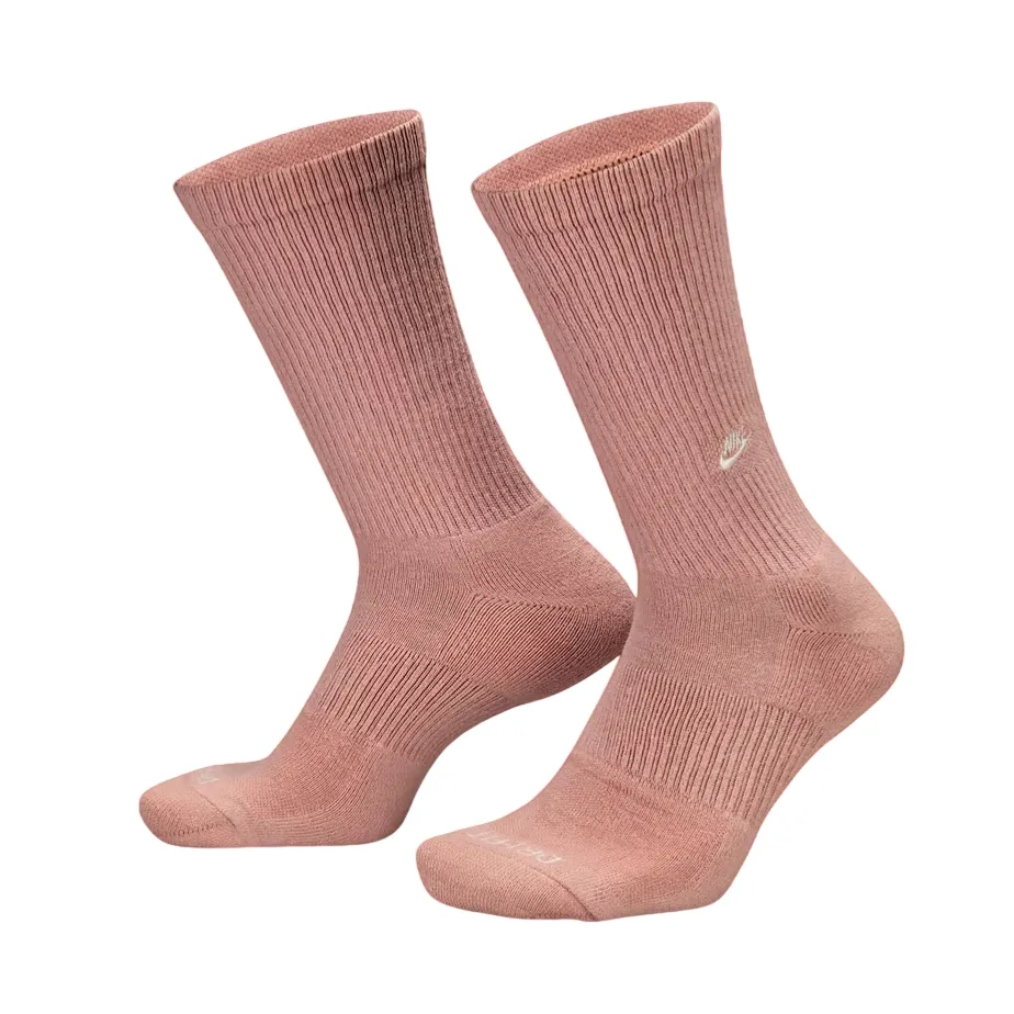 A pair of pink Nike crew socks with ribbed cuffs and small embroidered logos on the sides.