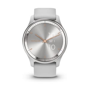 Garmin smartwatch with a sleek silver face, rose gold accents, and a gray textured strap. The watch displays the brand name \“GARMIN,\“ analog time, and digital date and time on the face.