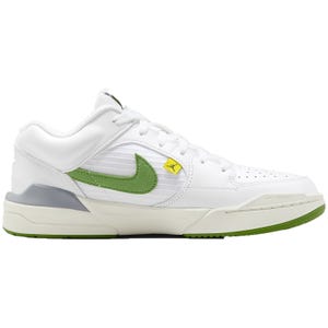 White sneakers with green and yellow accents, featuring a prominent Nike swoosh logo and a yellow Jordan emblem on the Velcro strap.