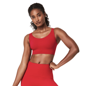 A woman is wearing a vibrant red athletic outfit consisting of a sports bra and high-waisted leggings.