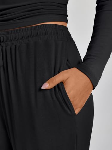 A person is wearing a black long-sleeve top and black pants with their hand in the pants pocket.