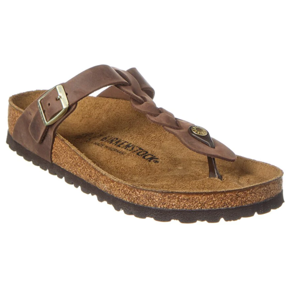 A brown Birkenstock sandal featuring a braided leather strap, buckle, and toe post, with a cork footbed and textured sole.