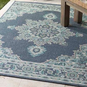 Blue and teal area rug with an intricate floral medallion pattern and decorative border, placed partially under a wooden bench.