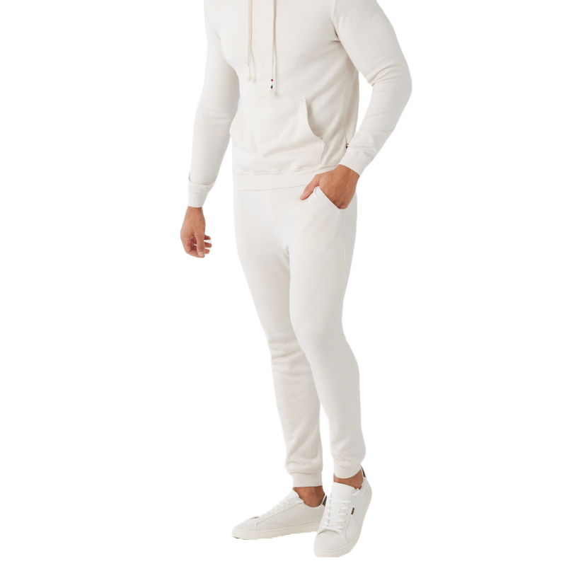 A person is wearing a white hoodie, white jogger pants, and white sneakers.