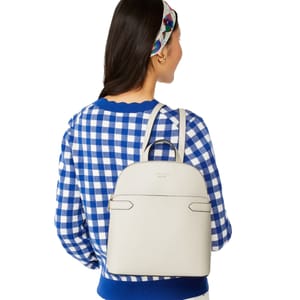 A person wearing a blue checkered sweater with a white backpack featuring subtle stitching lines.