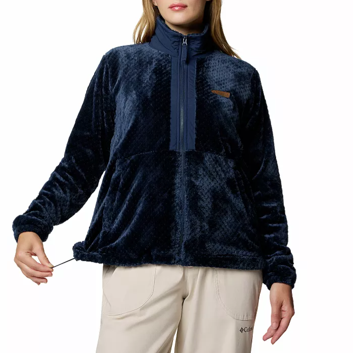 A woman is wearing a navy blue plush fleece pullover with a high collar and adjustable drawstring hem, paired with light-colored pants.