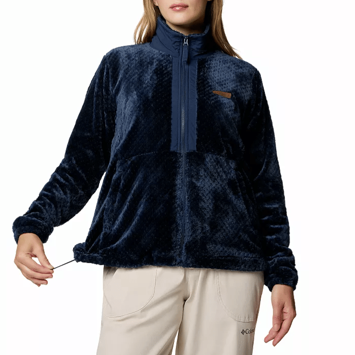 A woman is wearing a navy blue plush fleece pullover with a high collar and adjustable drawstring hem, paired with light-colored pants.