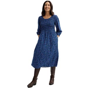 A woman is wearing a mid-length blue dress with a floral pattern, long sleeves, and boots.