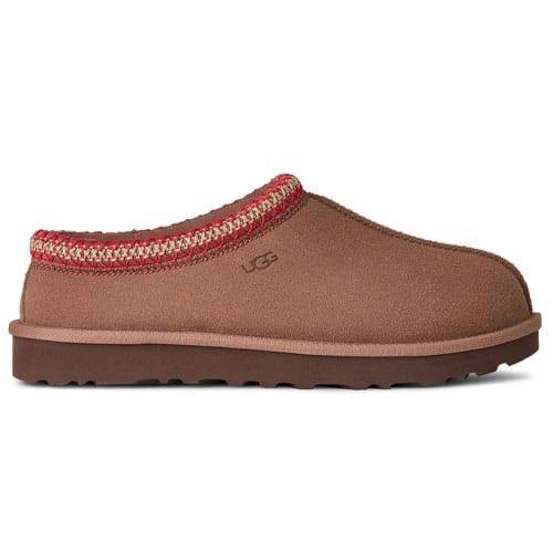 A brown suede UGG slipper with a red and tan woven trim around the opening, featuring a flat sole and slip-on design.