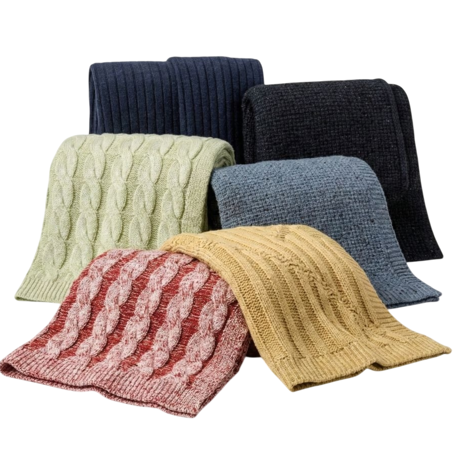 A collection of six folded knitted blankets in various colors and textures, including cable-knit patterns in green, red, and yellow, and ribbed designs in blue, black, and navy.