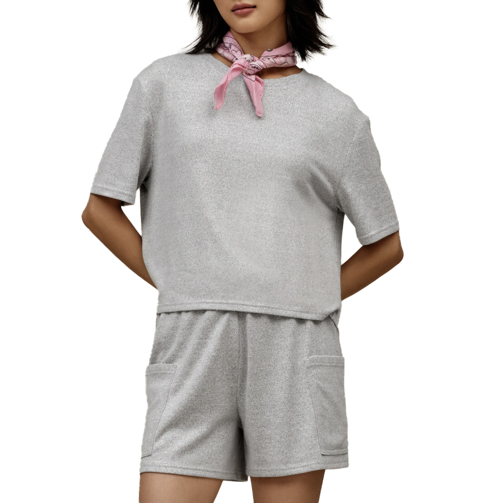 A woman is wearing a gray short-sleeve top and matching shorts with pockets, complemented by a pink bandana around her neck.