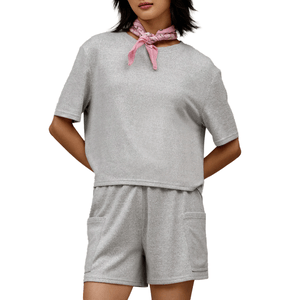 A woman is wearing a gray short-sleeve top and matching shorts with pockets, complemented by a pink bandana around her neck.
