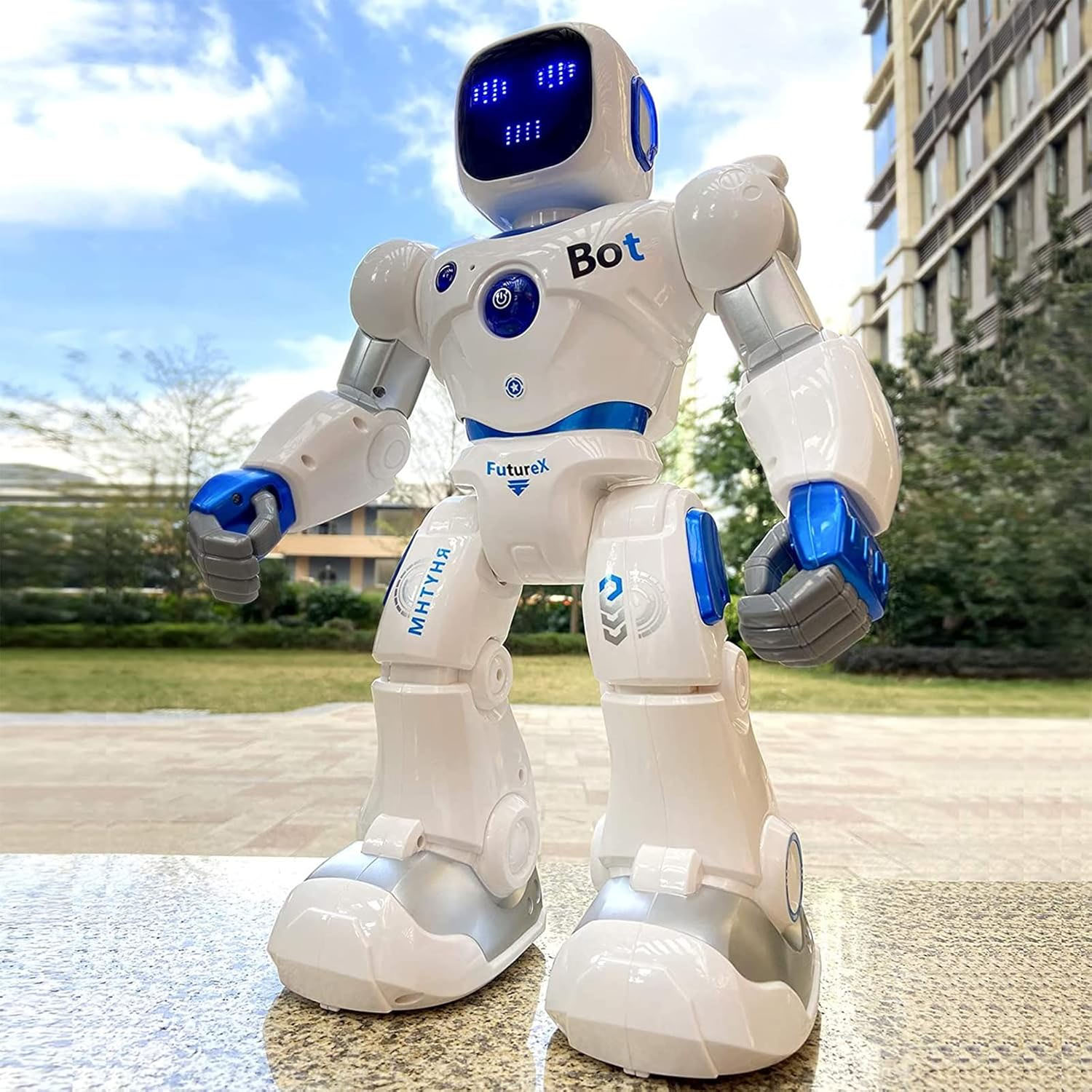 A white and blue robot toy with a screen face and movable limbs, featuring decals like \“Bot\“ and \“FutureX,\“ designed for programmable and remote-controlled interaction.