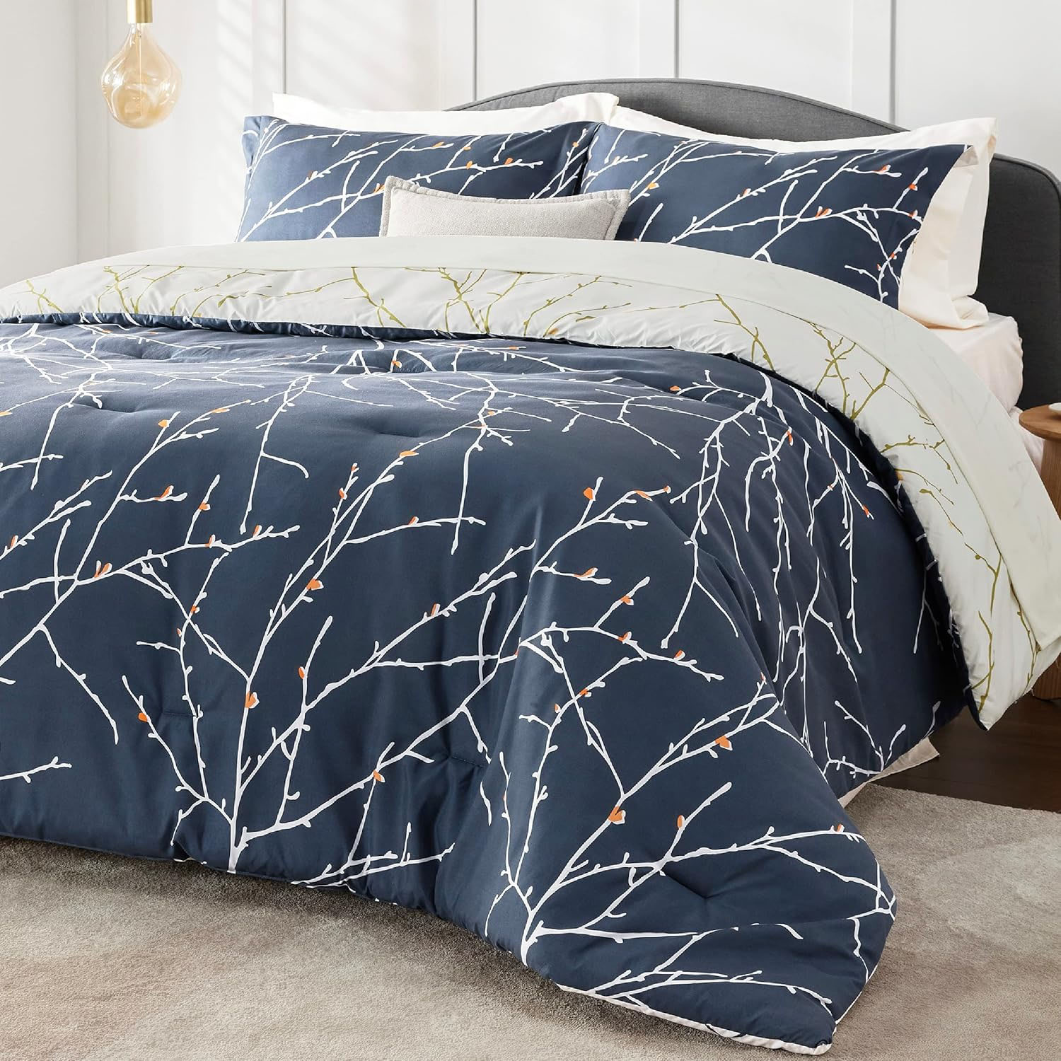A bedding set featuring a duvet cover and pillowcases with a navy background and a minimalist branch pattern.