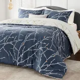 A bedding set featuring a duvet cover and pillowcases with a navy background and a minimalist branch pattern.