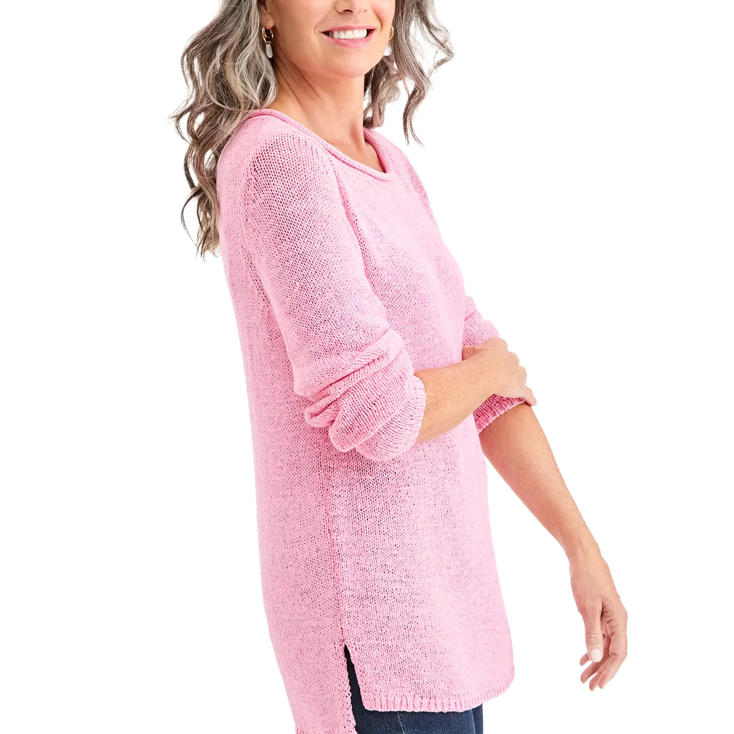 A woman wearing a pink knitted sweater with long sleeves and slit sides, paired with blue jeans.