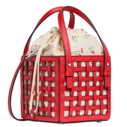 A red woven leather bucket bag with a short handle and crossbody strap, featuring a drawstring canvas pouch inside with a floral print.