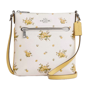 Coach Outlet Leather Floral Crossbody features a floral print on a white leather background with a front zip pocket, yellow strap, and signature Coach tag.