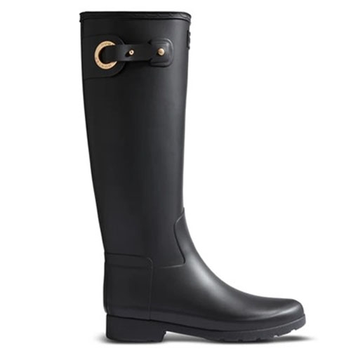A tall black rubber rain boot features a decorative gold buckle and strap detail near the top.