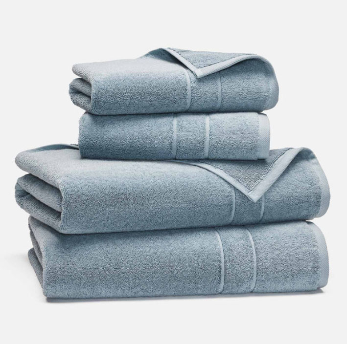 A stack of folded light blue towels in varying sizes, displayed against a white background.