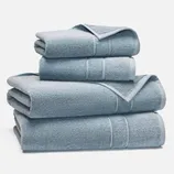 A stack of folded light blue towels in varying sizes, displayed against a white background.