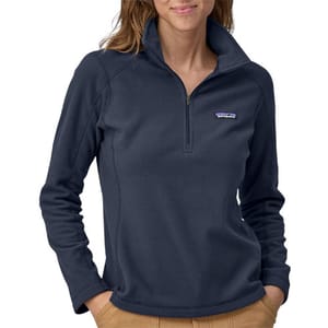 A woman wearing a blue Patagonia quarter-zip fleece pullover with a logo on the chest and tan pants.