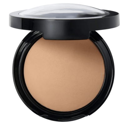A compact powder foundation in a round black case with a transparent, domed lid, displaying a light beige shade.