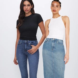 Two women wearing high-waisted jeans, one in a black shirt and the other in a white tank top.
