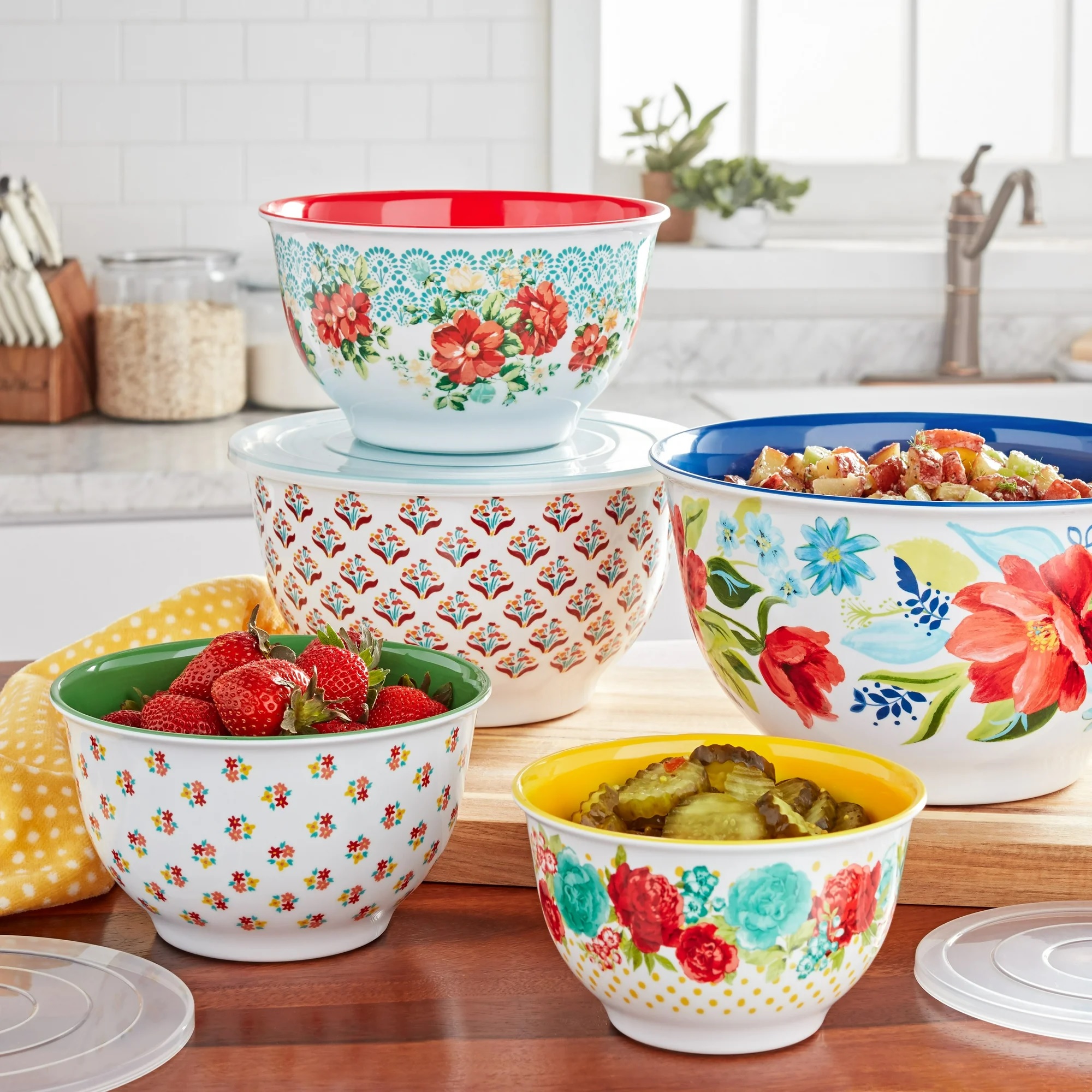 A set of colorful mixing bowls with floral patterns, containing strawberries and a fruit salad.