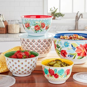 A set of colorful mixing bowls with floral patterns, containing strawberries and a fruit salad.
