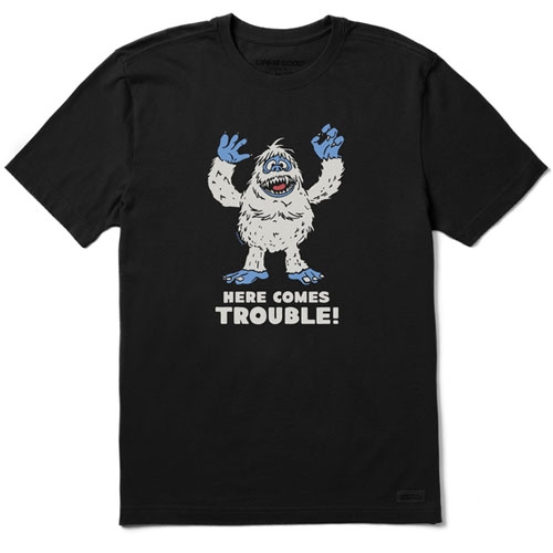 Black T-shirt featuring a cartoon yeti with blue hands and feet, and the text \“HERE COMES TROUBLE!\“ written below the image.