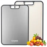 Dual-sided cutting board with a stainless steel side and a textured non-slip side, trimmed in gray, accompanied by a basket of fruits and vegetables.