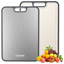 Dual-sided cutting board with a stainless steel side and a textured non-slip side, trimmed in gray, accompanied by a basket of fruits and vegetables.