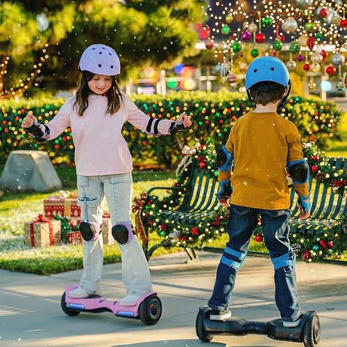Two children wearing helmets and protective gear are riding hoverboards in a festive outdoor setting with holiday decorations and wrapped gifts.