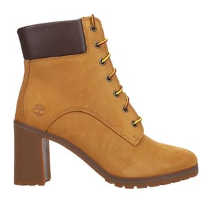 A tan, high-heeled ankle boot with yellow laces, featuring a padded dark brown collar and rubber lug sole, embossed with the Timberland logo.