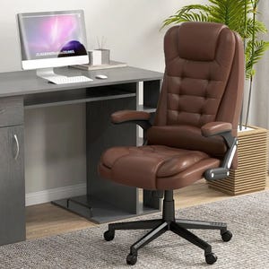 A brown leather office chair with a high backrest and armrests is positioned in front of a gray desk holding a modern computer setup, with decor elements like plants and accessories.