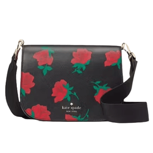 Kate Spade New York rose-printed saddle bag with black background, features red rose motifs, gold hardware, and a black adjustable strap.