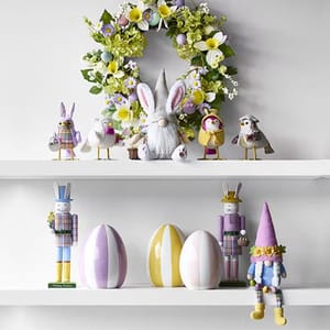 A decorative display with a floral wreath, a plush gnome, and assorted animal figurines on the upper shelf; the lower shelf has pastel-striped egg decorations and whimsical bunny figures.