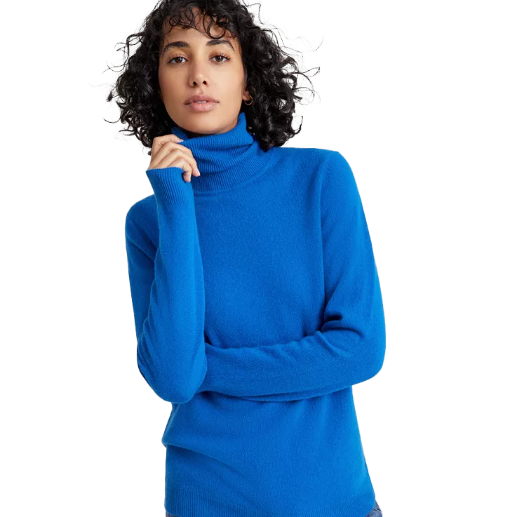 A woman wearing a bright blue turtleneck sweater with long sleeves and a relaxed fit.