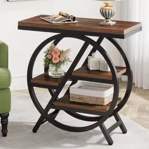 A modern end table featuring a wooden top and three-tier shelving with circular metal frame design, holding a lamp, a vase with flowers, decorative boxes, and a wicker basket.