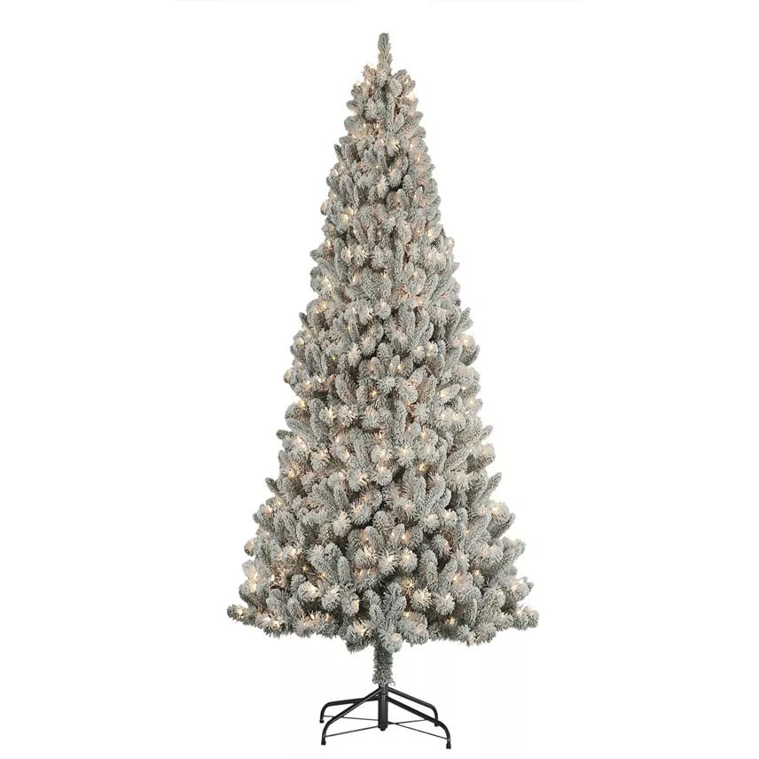 A frosted artificial Christmas tree with dense, snow-dusted branches, mounted on a metal stand, pre-lit with warm white lights.
