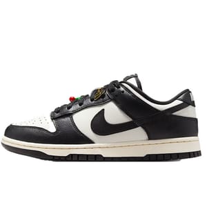 Black and white Nike Dunk Low sneakers with a beige sole and a colorful lace accent.