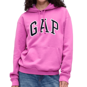 A pink hoodie featuring the word \“GAP\“ in bold, black letters with a front pocket and ribbed cuffs, paired with blue jeans.