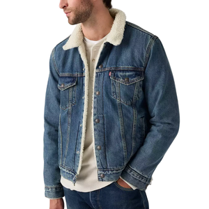 A man is wearing a blue denim jacket with a white shearling collar, paired with a white shirt and blue jeans.