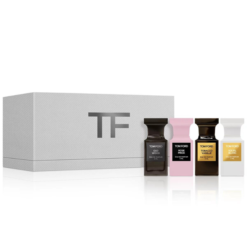 Four small bottles of Tom Ford fragrances are displayed next to a textured white box with the initials 'TF' on the front. Each bottle has a different colored label.